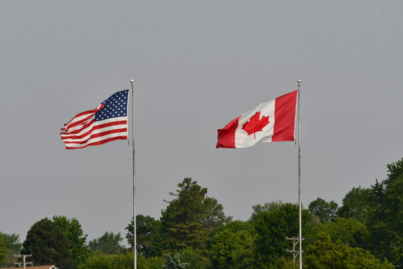 Canadian and American flags flying side by side representing non-resident property sales in Canada