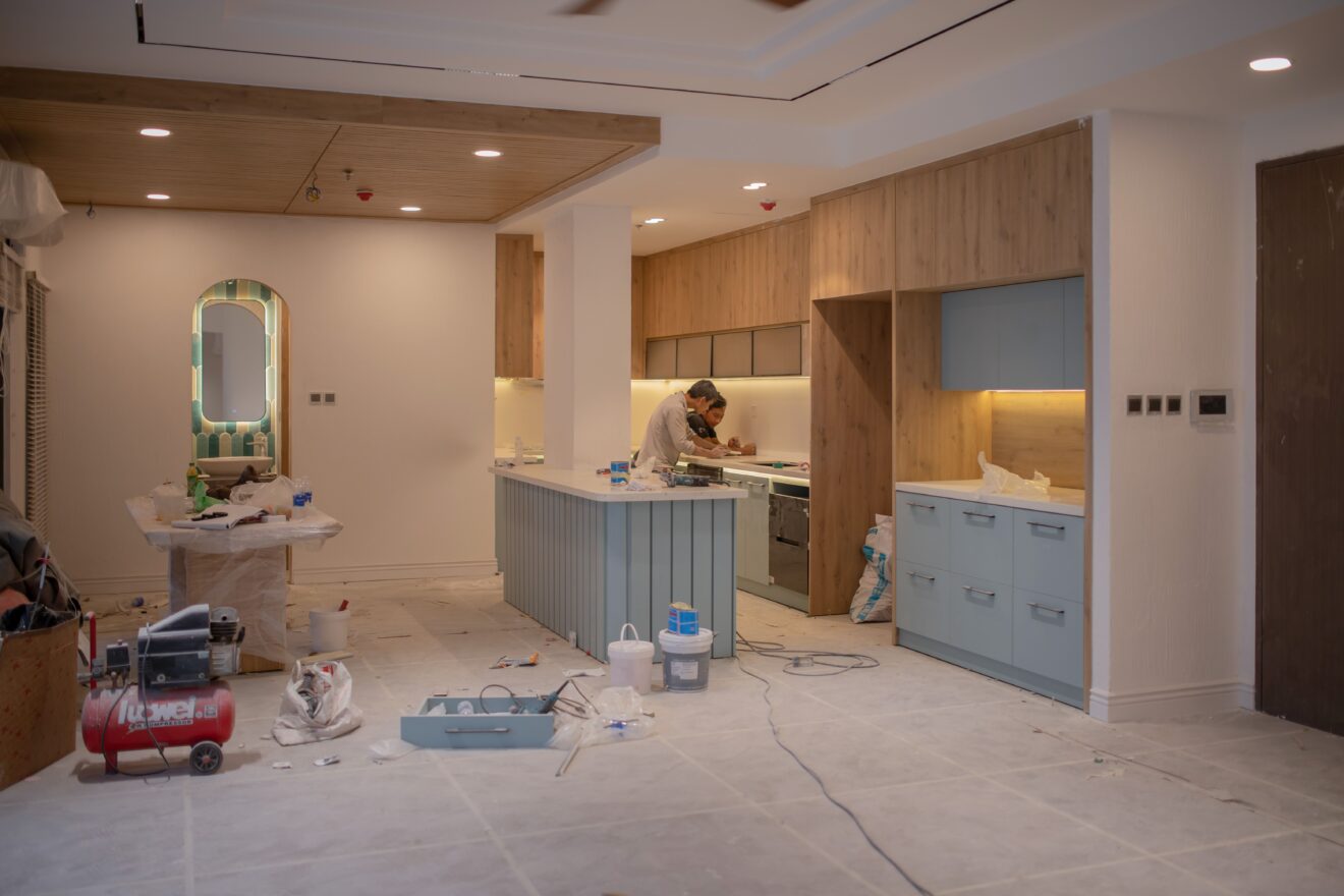 Worker renovating a modern kitchen with wood cabinets and a blue island.