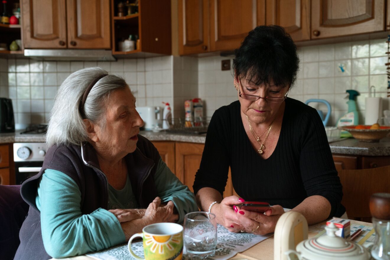 Adult daughter and her elderly mother sitting together at a kitchen table, with the heading Selling a parent's home in Ontario, a start-here guide from Damir Strk